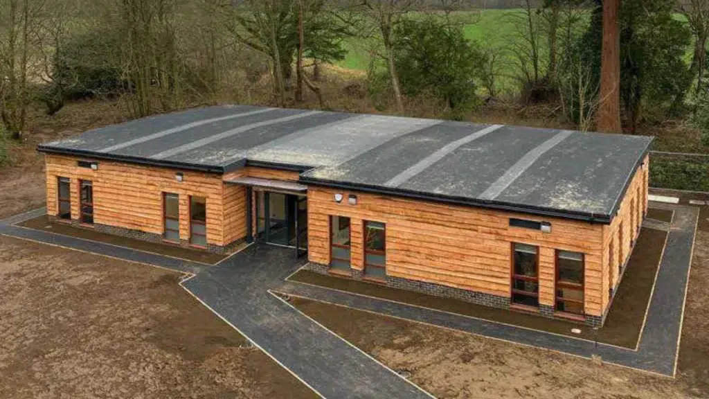 Modern inclusive learning environment featuring sustainable timber-clad modular school building with accessible entrance, designed to support SEND education with natural materials and inclusive design principles