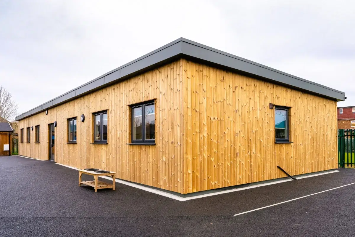 Modular SEND School Building | Hedgewood School Timber-clad modular SEND school building with accessible wooden ramp and anthracite windows. Single-storey special needs classroom facility at Hedgewood School featuring natural larch cladding.