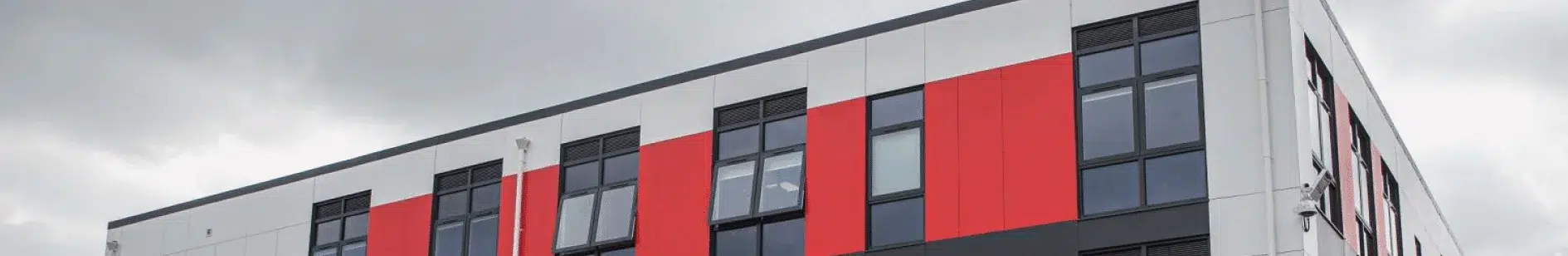 Three-storey modular humanities block featuring red and white exterior design with full-height windows, built for Fred Longworth High School Manchester
