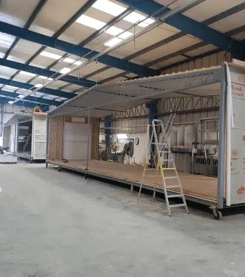 ModuleK's manufacturing centre showcasing a modular building section during assembly, with exposed framework and construction equipment in a controlled factory environment